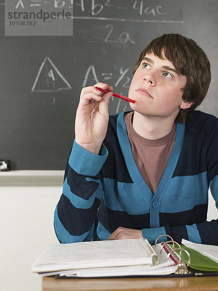 Denkender Schüler am Schreibtisch im Klassenzimmer