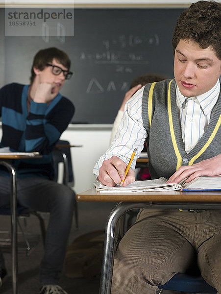 Schüler schreibt Notizen am Schreibtisch im Klassenzimmer