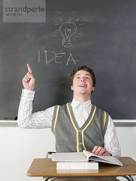 Schüler mit Idee unter Glühbirne auf Tafel im Klassenzimmer