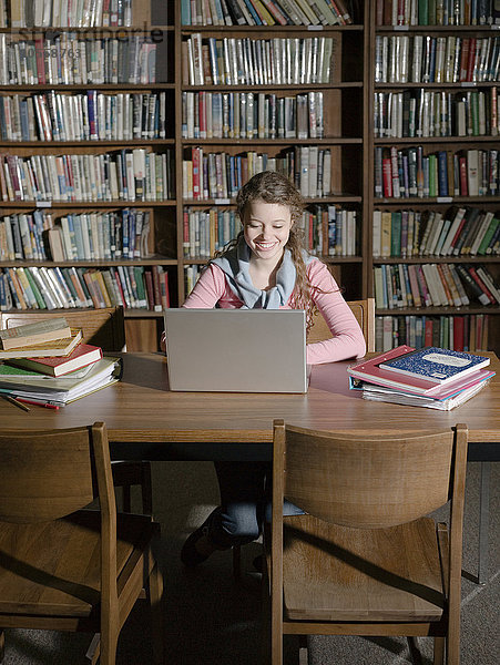 Studentin benutzt Laptop in der Bibliothek