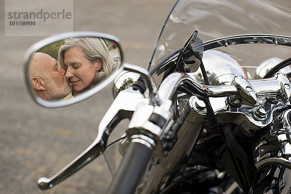 Älteres Paar küsst sich im Motorradseitenspiegel