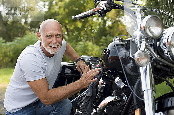 Älterer Mann repariert Motorrad