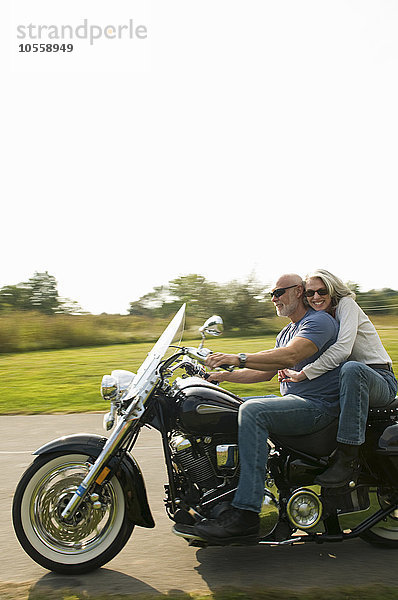 Älteres Paar fährt Motorrad auf einer Landstraße