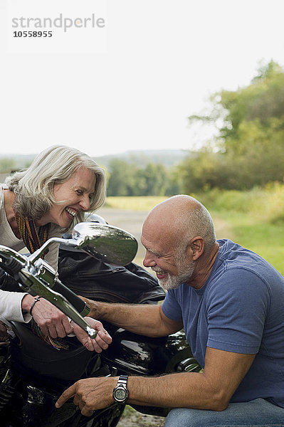 Älteres Paar repariert Motorrad im Park
