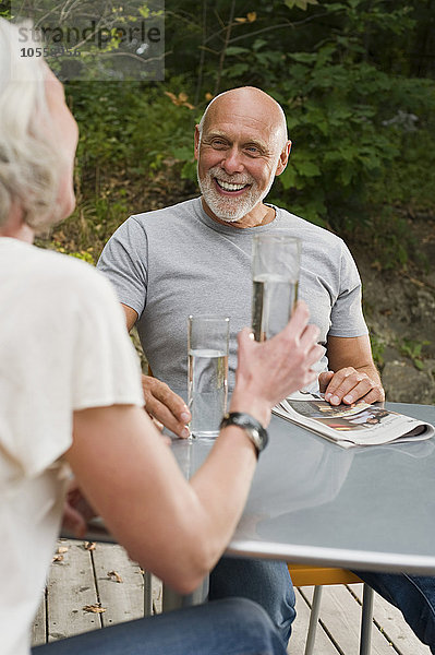 Älteres Paar trinkt Wasser an einem Tisch im Freien