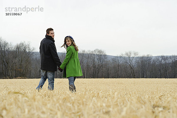 Kaukasisches Paar geht in einem ländlichen Feld spazieren