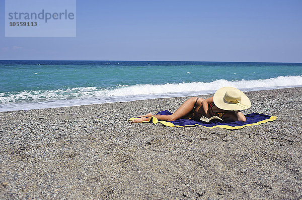 Frau beim Sonnenbaden und Lesen am Strand