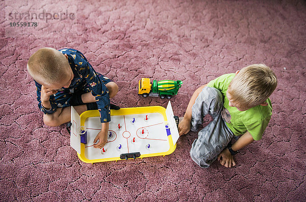 Kaukasische Brüder spielen Eishockey auf dem Boden