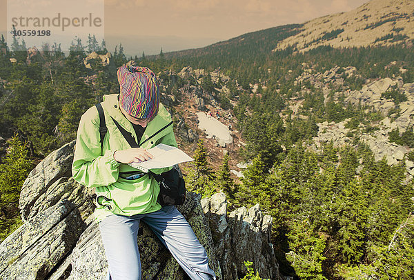 Kaukasischer Wanderer  der auf einer Bergkuppe eine Karte liest