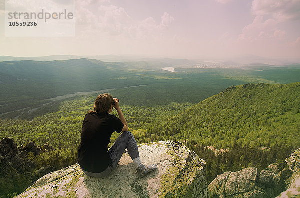 Kaukasischer Wanderer bewundert abgelegene Landschaft von einer felsigen Bergkuppe aus