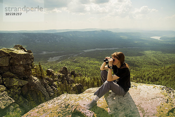 Kaukasischer Wanderer bewundert abgelegene Landschaft von einer felsigen Bergkuppe aus