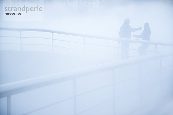 Menschen stehen auf einem Gehweg im Nebel