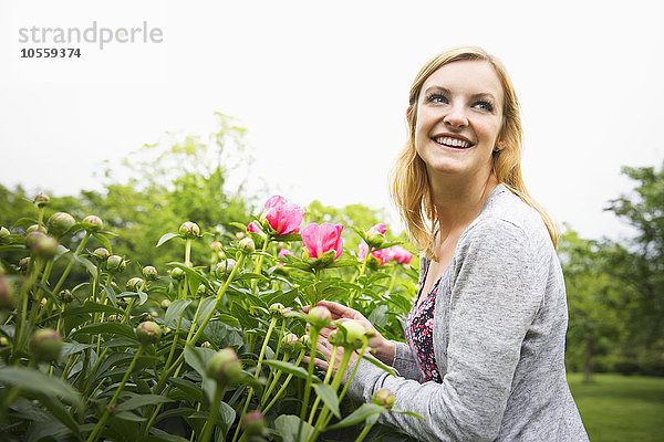 Kaukasische Frau riecht an Blumen im Park