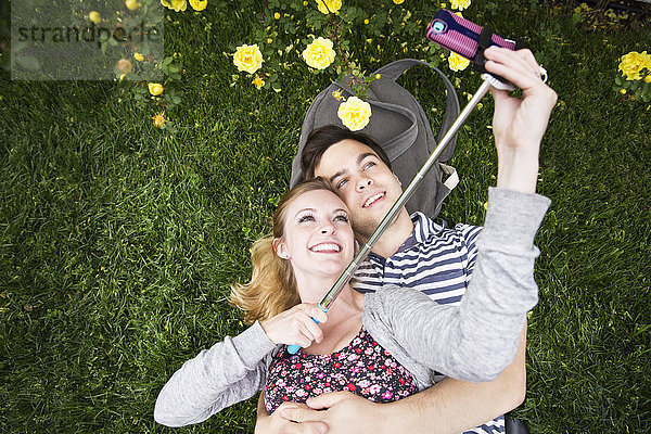Kaukasisches Paar macht Selfie mit Handy im Gras