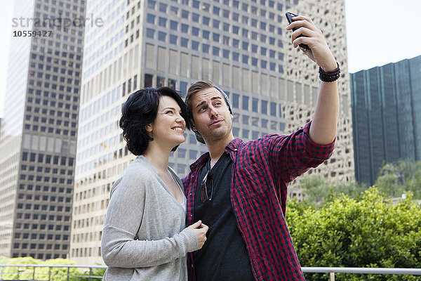 Kaukasisches Paar macht Selfie mit Handy in der Stadt