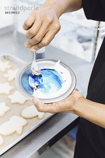 Nahaufnahme eines Bäckers  der blauen Zuckerguss in einer Bäckerei herstellt