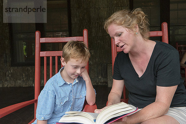 Kaukasische Mutter und Sohn lesen auf der Terrasse