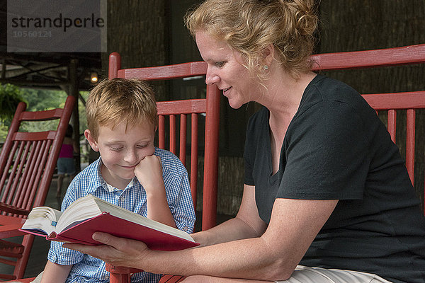 Kaukasische Mutter und Sohn lesen auf der Terrasse