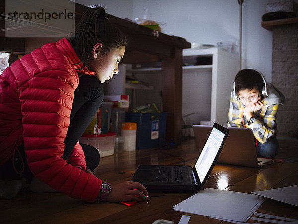 Gemischtrassige Kinder benutzen Laptops auf dem Boden