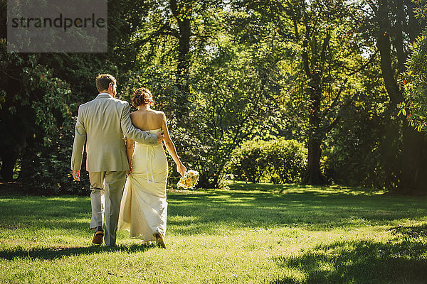 Kaukasische Braut und Bräutigam gehen im Gras