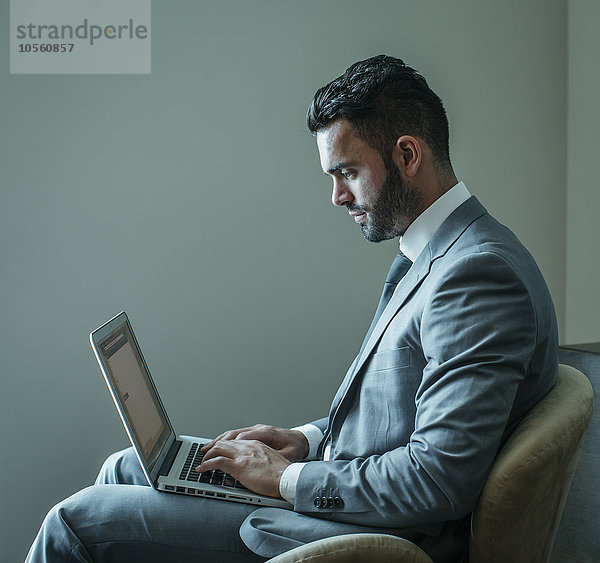 Geschäftsmann mit Laptop im Sessel