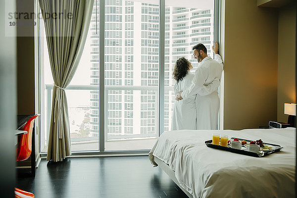 Paar umarmt sich im Bademantel im Hotelzimmer