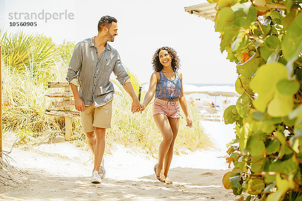 Paar hält Hände und geht am Strand spazieren