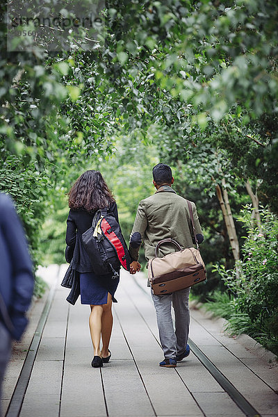 Paar geht auf Holzsteg im Park