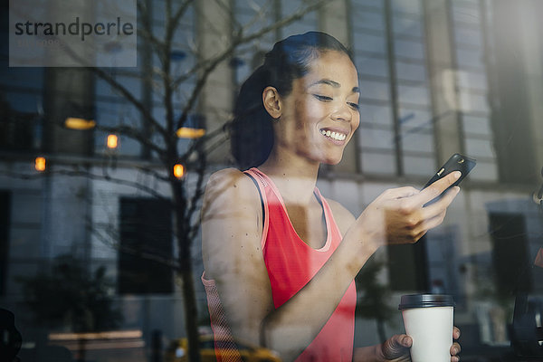 Gemischtrassige Frau benutzt Mobiltelefon in einem Café