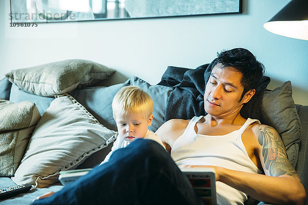 Vater und Sohn lesen auf dem Sofa im Wohnzimmer