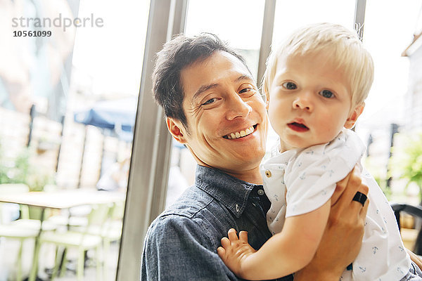 Lächelnder Vater hält seinen Sohn am Fenster