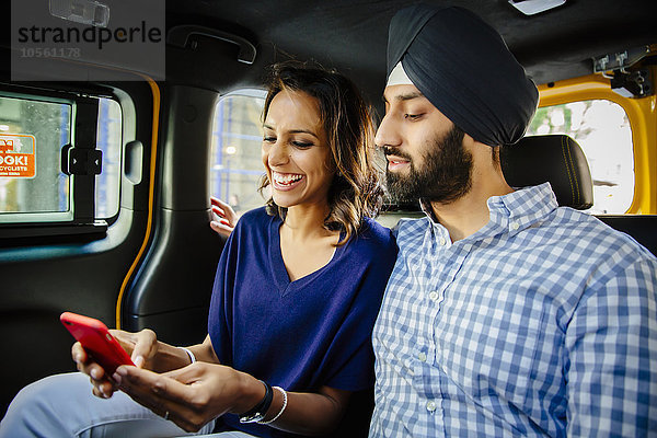 Indisches Paar benutzt Handy im Taxi