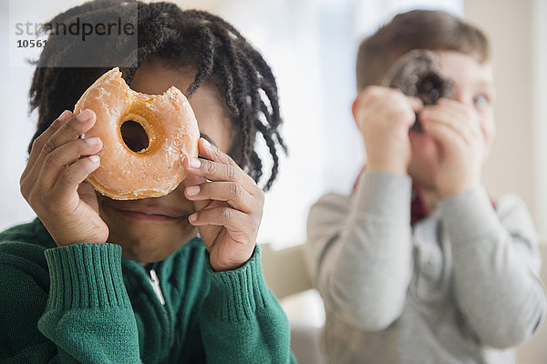 Jungen spähen durch Donut-Löcher