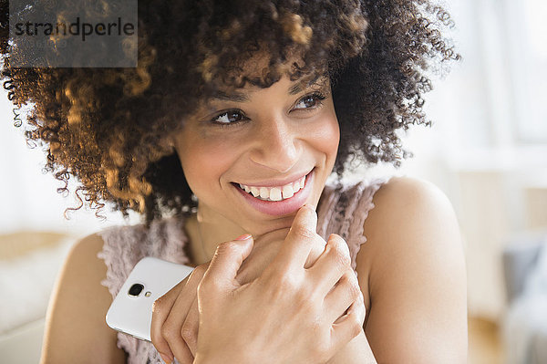 Lächelnde  gemischtrassige Frau mit Mobiltelefon