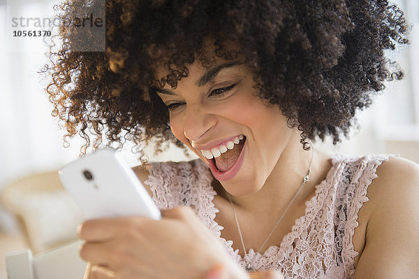 Lächelnde gemischtrassige Frau  die ein Mobiltelefon benutzt