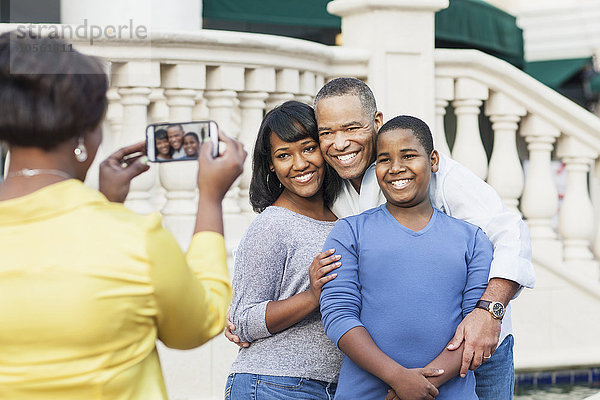 Afroamerikanische Frau fotografiert ihre Familie mit dem Handy