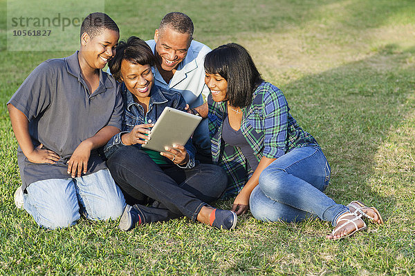 Afroamerikanische Familie benutzt digitales Tablet auf einer Wiese