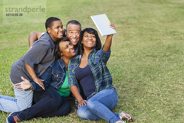 Afroamerikanische Familie macht Selfie mit digitalem Tablet im Gras