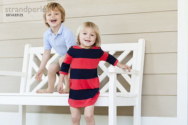 Kaukasischer Bruder und Schwester spielen auf der Veranda