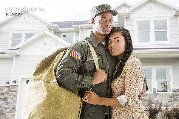 Heimkehrender Soldat und Frau stehen vor dem Haus