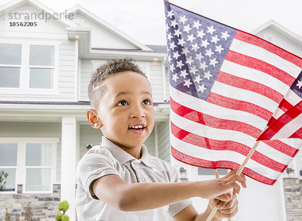 Gemischtrassiger Junge schwenkt amerikanische Flagge