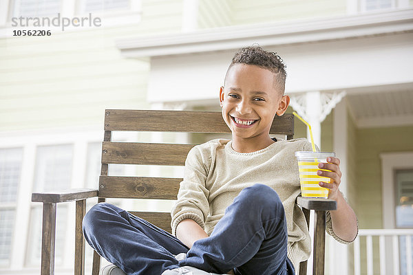 Schwarzer Junge trinkt Orangensaft im Hinterhof