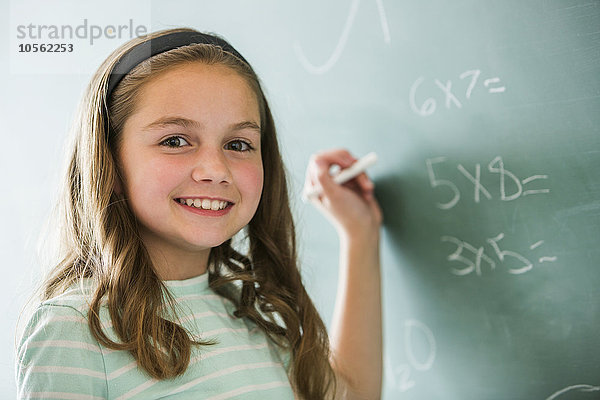 Kaukasisches Mädchen macht Matheaufgaben auf der Kreidetafel