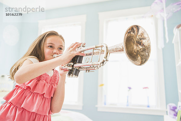Kaukasisches Mädchen spielt Trompete im Schlafzimmer