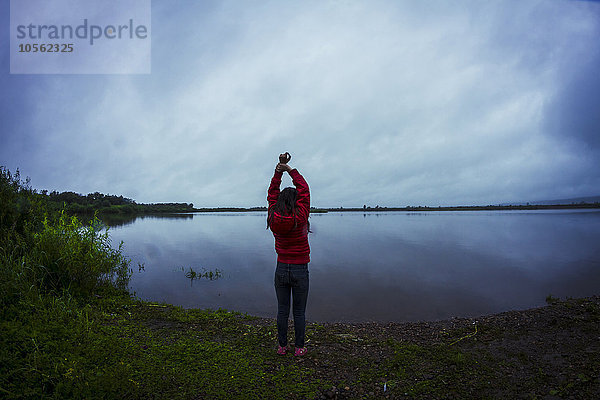 Kaukasisches Teenager-Mädchen streckt sich an einem abgelegenen See