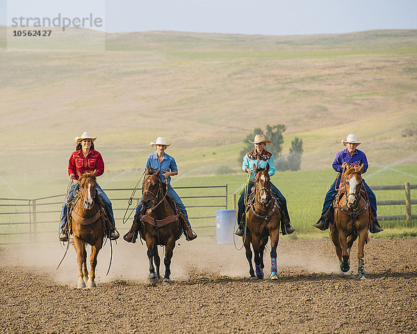 Cowgirls und Cowboy reiten Pferde auf Ranch