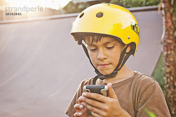 Gemischtrassiger Junge mit Helm und Mobiltelefon