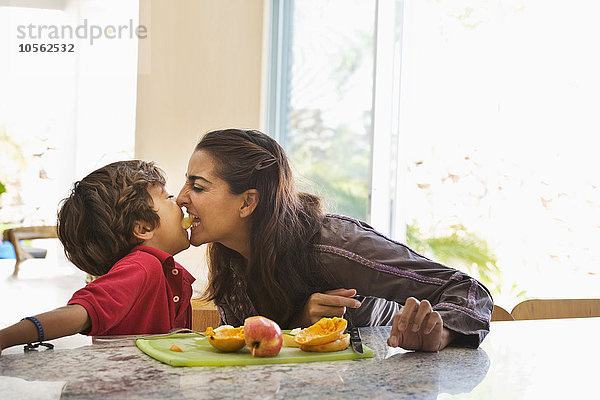 Hispanische Mutter und Sohn essen Obst in der Küche