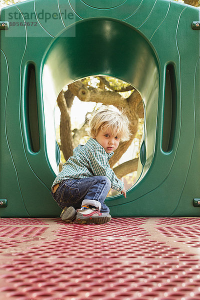 Kaukasischer Junge klettert auf Spielgerät auf Spielplatz