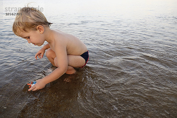 Kaukasischer Junge spielt im Wasser am Strand